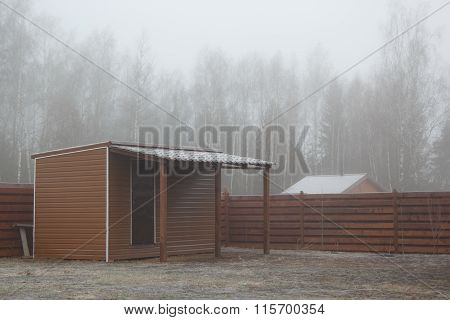 Barn With Shed On Frozen Lawn In Mist