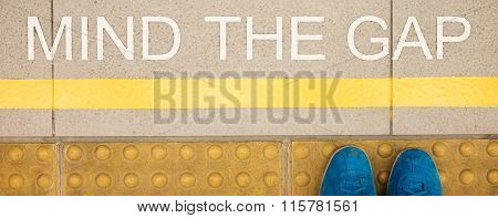 The sign Mind the gap painted on train station's platform edge