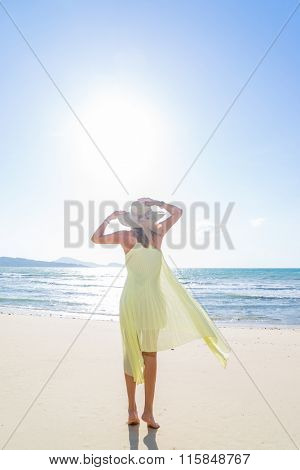 Woman walking on the trpical  beach in yellow dress