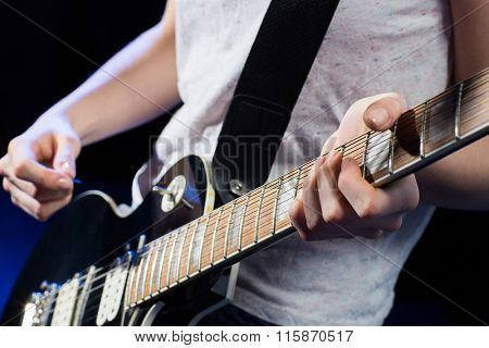 musician playing electric guitar with mediator