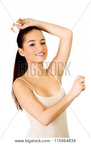 Young woman applying anti perspirant.