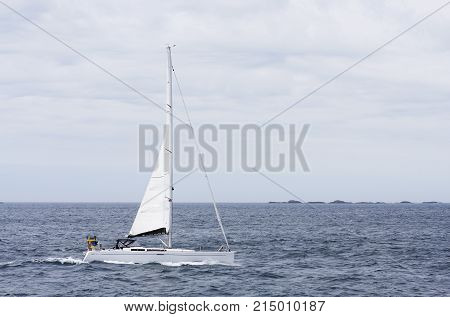 NORTH SEA, NORWAY ON JULY 04. View of a Swedish sailboat in tailwind on July 04, 2010 in North Sea, Norway. Islands in the background, unidentified people. Editorial use.