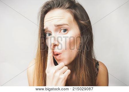 Young woman foung acne on the nose,looks upset