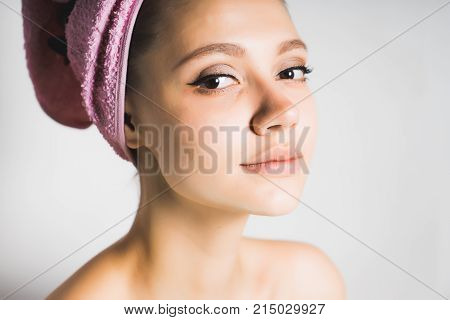 young cute girl with clean skin, with a pink towel on her head looking at the camera, smiling