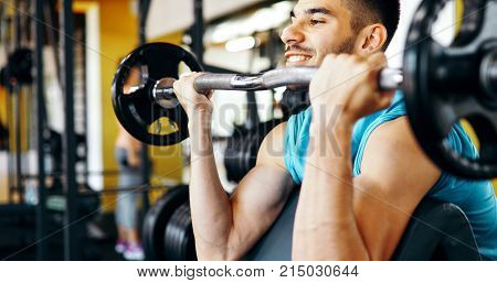 Strong ripped man training bicepses in gym
