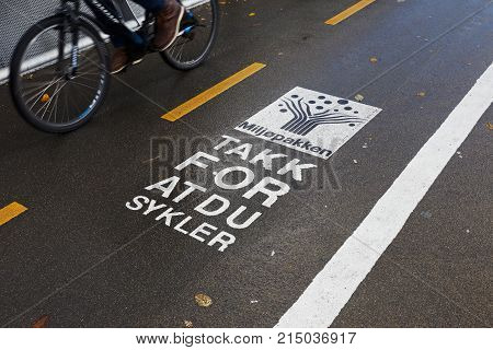 Trondheim Norway - October 16 2017: One bicycle passing a sign on the bicycle track with a message fromm the Tronheim enviroment project Miljopakken with text in Norwegian translated to English reading Thanks for cycling.