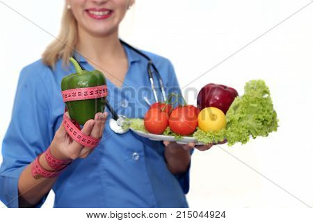 White-headed girl doctor dietitian on a white background. A doctor holds a green pepper and soft meter in a hand