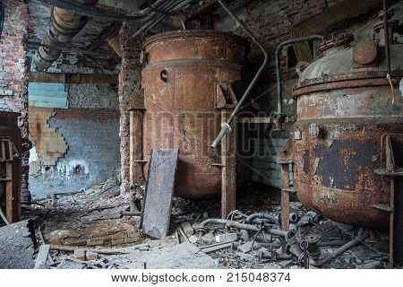 Rusty industrial containers for nitric acid in abandoned factory.