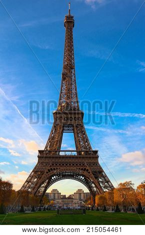 Color fall image of the Eiffel tower in Paris, France, Europe, on a sunny autumn day with blue sky and colorful leaves .