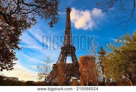 Color fall image of the Eiffel tower in Paris, France, Europe, on a sunny autumn day with blue sky and colorful leaves .