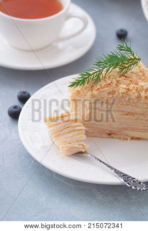 Round multi-layered cake Napoleon with custard on a light-blue table background. Selective focus. Toned.