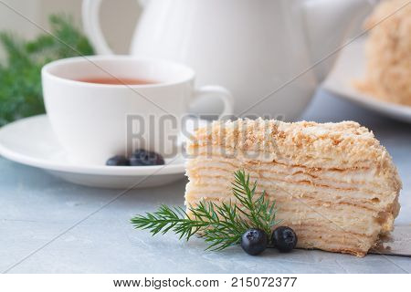 Round multi-layered cake Napoleon with custard on a light-blue table background. Selective focus. Toned.