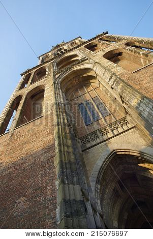 Vertical close up view on brown brick old antique church bell tower. Classic Europe European church cathedral bell tower. Classic brick church architecture in Utrecht city Holland