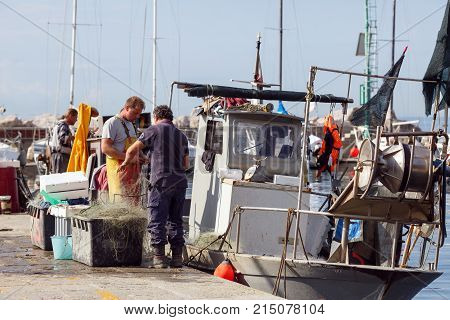 TRIESTE/ ITALY - OCTOBER 9, 2017. Two Fishermen standing near their fishing trawler. Trieste, region Friuli-Venezia Giulia, Italy.