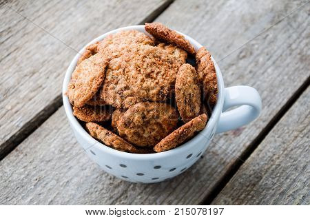 Chocolate cookies in coffee cup on the wooden table.