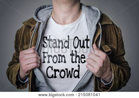 Man showing Stand Out From The Crowd tittle on t-shirt. Talent and uniqueness concept.