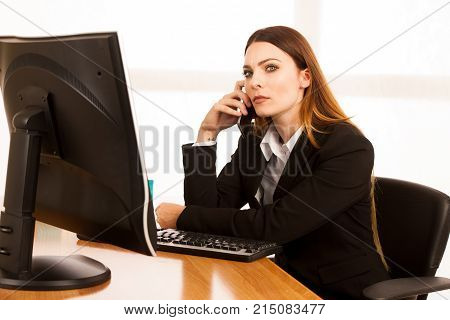 Angry Business Woman Talks On Smert Phone In Office At Her Desk