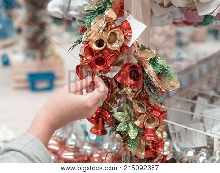 Cheerful happy customer girl choosing Christmas tree or New Year's decoration bells