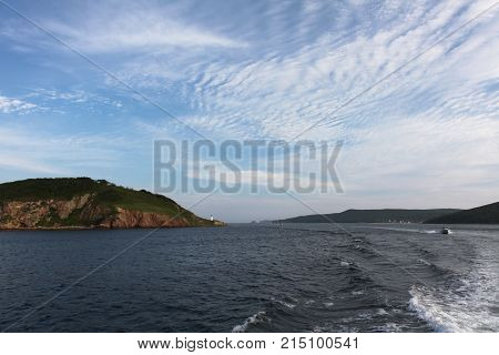 The trail from the boat to the sea surface. The shore. Lighthouse. Seascape.