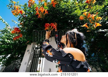 Fashion woman posing outdoor in orange flowers