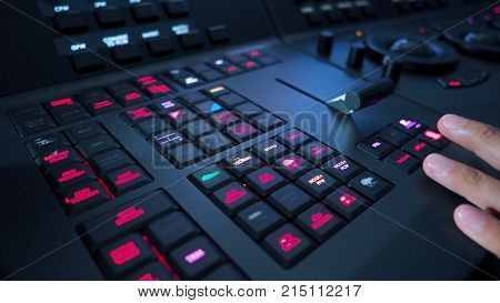 Telecine controller machine and man hand editing or adjusting color on digital video movie or film in the post production stage.