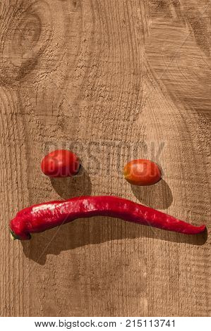 hili and tomatoes on an old wooden board laid out in the form of an emoticon