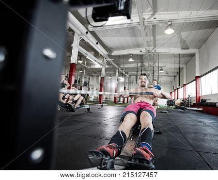 Determined Male Pulling Rowing Machine's Handle