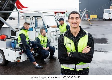 Worker Standing Arms Crossed While Colleagues Communicating At G