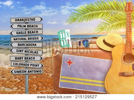 Concept of summer traveling with old suitcase and Aruba town sign with burning sun