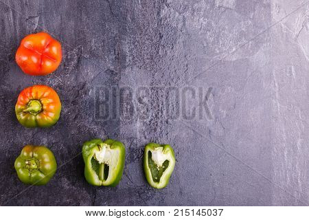 Appetizing, juicy, Bulgarian pepper, cut in half, and whole, orange and green, on a black background. Top view, free space for text.