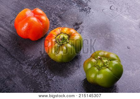 Appetizing, juicy, Bulgarian pepper, decomposed orange and green, mature, and half-ripe, on a black background