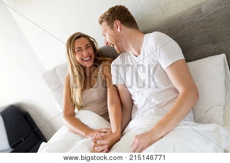 Laughing and giggling couple in bed hacing fun
