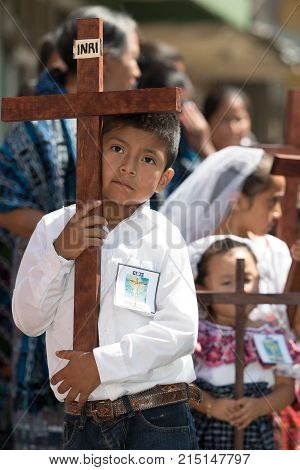 March 25, 2016 San Pedro la Laguna, Guatemala: a young boy holds a wooden cross during Easter procession