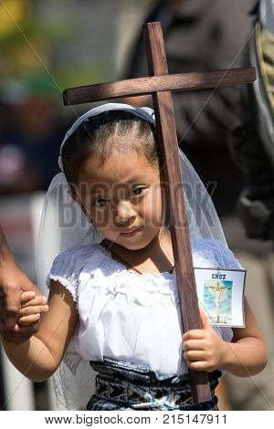 March 25, 2016 San Pedro la Laguna, Guatemala: young mayan girl dressed in traditional clothes holding a wooden cross at Easter procession