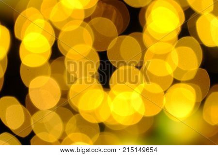 Blurred warm lights of a christmas tree with dark night background,yellow bulbs and colorful bokeh