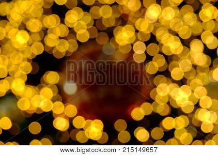Blurred warm lights of a christmas tree with dark night background,yellow bulbs and colorful bokeh
