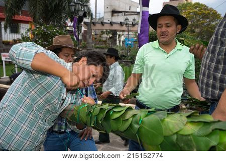 March 25, 2016 San Pedro la Laguna, Guatemala: mayan men tying green leafs on wooden pole for decoration during Easter celebration