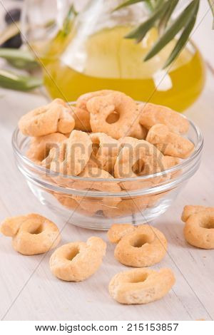 Italian taralli with olive oil and spices on wooden table.
