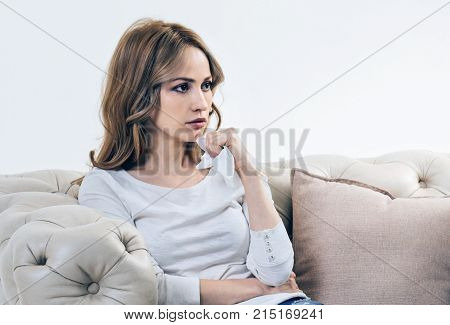 Difficult life period. Depressed sad young woman holding a paper tissue and feeling upset while being preoccupied with her problems