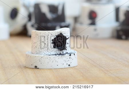 Several Plastic Nozzles From A Paint Sprayer That Lie On A Wooden Surface Against A Gray Wall Backgr