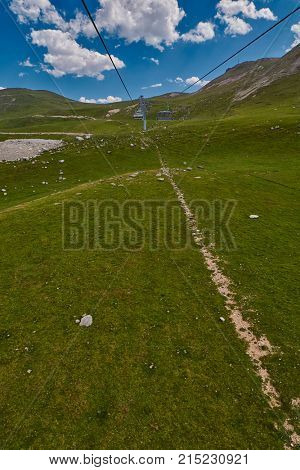 Aerial ropeway high in the mountains of Caucasus with grass plains and cow pastures in the background