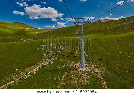 Aerial ropeway high in the mountains of Caucasus with grass plains and cow pastures in the background