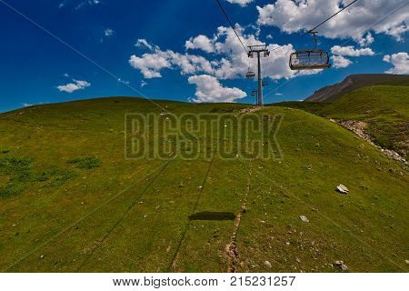 Aerial ropeway high in the mountains of Caucasus with grass plains and cow pastures in the background