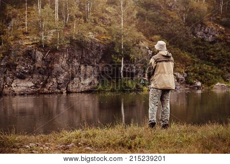 Fishing. Fisherman on the river catches fish throws the fishing rod and pulls the prey on the spinning