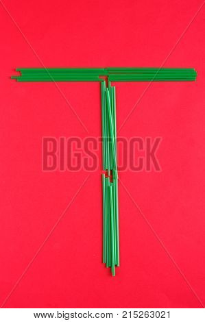 A bunch of green-colored cocktail tubes are lined in the shape of a letter T on a red background.