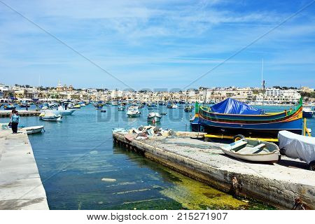 MARSAXLOKK, MALTA - APRIL 1, 2017 - Traditional Maltese Dghajsa fishing boats in the harbour with waterfront Marsaxlokk Malta Europe, April 1, 2017.