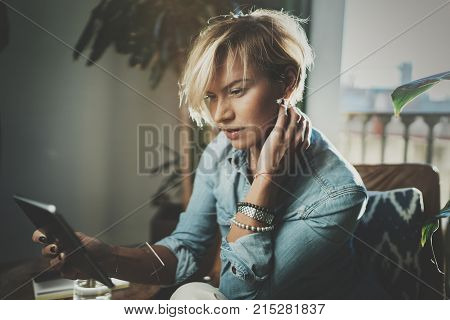 Smiling young woman wearing casual clothes and using electronic device while spending relax time in vacation travel.Attractive woman owner communicating on digital tablet.Blurred background