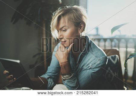 Smiling young woman wearing casual clothes and using electronic device while spending relax time in vacation travel.Attractive woman owner communicating on digital tablet.Blurred background