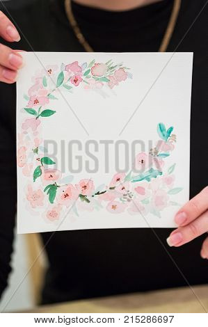 art, creation, background concept. in thin fingers of woman with tidy manicure there is pattern for birthday card with hollow center for text and decorated with painted flowers edges
