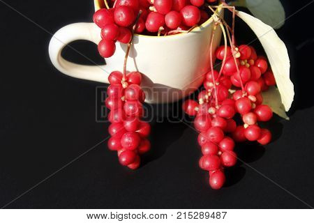 schizandra and leaves in the cup on the dark background. Crop of schizandra
